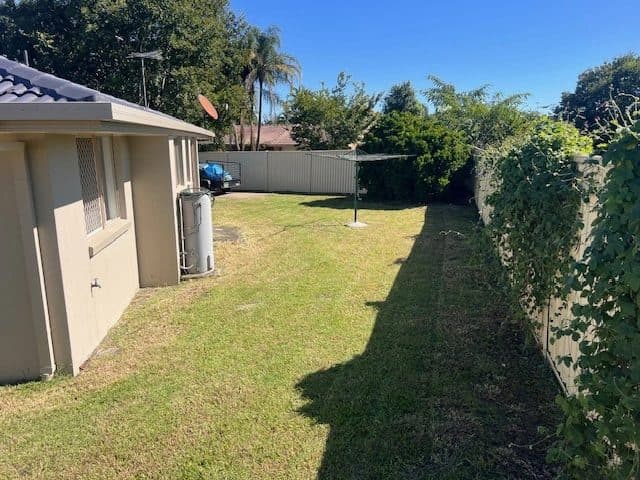 Mown side yard with a clothesline beside a house
